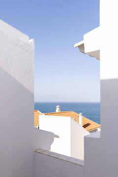 white architectural house by the sea with orange tiled roof with blue ocean in the background, minimal, negative space