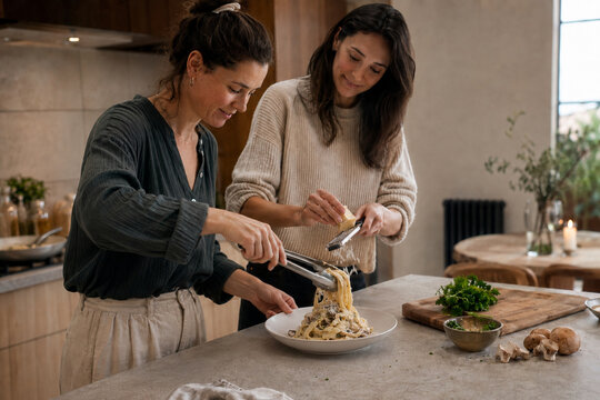 Two Friends Preparing Creamy Pasta Together at Home