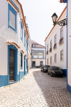 picturesque traditional blue and white homes with orange tiled roofs on cobblestone streets in Ericeira, Portugal