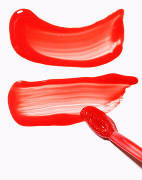 two red lip gloss smears with applicator, cosmetics beauty product texture, liquid blush, lipstick swatch with brush