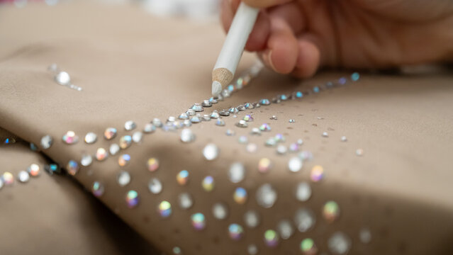 A woman decorates her gymnastics costume with rhinestones. Rhythmic gymnastics. 