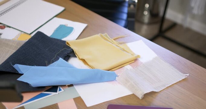 Camera is pushing in, rising, focusing on swatches and color chips on table to center pile