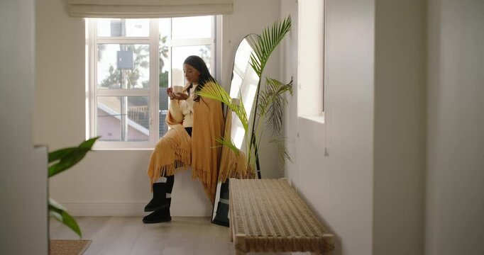 Adult African American woman sitting nook mustard shawl sipping mug gazing palm view cam moving in
