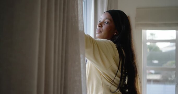 African American woman entering right touching curtains pulling aside checking balcony at home