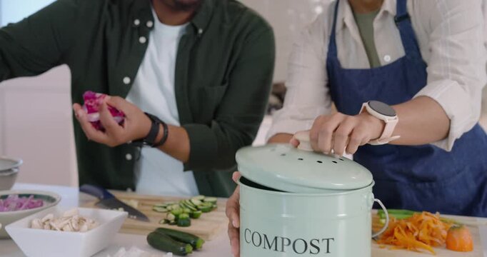 African American couple cutting at kitchen island as woman bringing compost bin man dropping peels