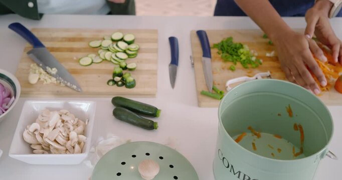 African American couple chopping veg opening compost pail tossing peels high-fiving prepping meal