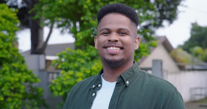 African American man reacting to offscreen joke, smiling into laughter in yard green overshirt