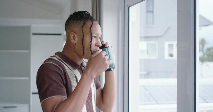African American man in brown polo answering smartphone, sipping green mug at apt window chatting