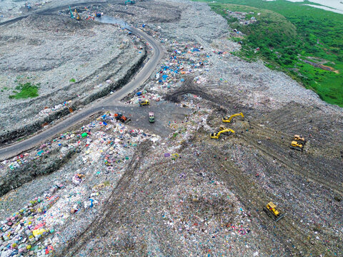 Aerial view of Amin Bazar Waste Disposal Area with excavators working on large piles of waste and dirt roads, Bongaon Union, Dhaka Division, Bangladesh.