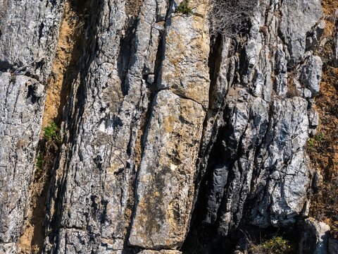 Aerial view of the rocky cliffs at Praia Grande featuring ancient dinosaur footprints in limestone strata with rugged textures and geological formations in Colares, Lisboa, Portugal.