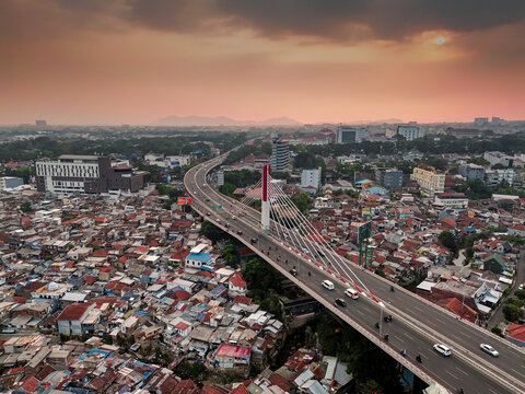 Aerial view of the Pasupati Bridge spanning over the dense urban landscape of Bandung with traffic flowing during sunset in Bandung, West Java, Indonesia.