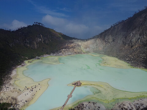 Aerial view of Kawah Putih Ciwidey with its turquoise volcanic lake, wooden pier, and surrounding crater walls in Bandung, West Java, Indonesia.