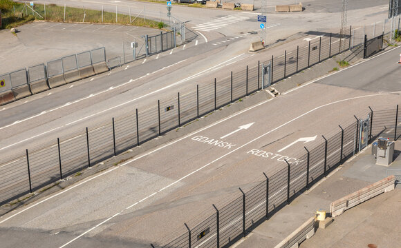 Aerial view of the port terminal area in Nynashamn with road markings directing traffic to Gdansk and Rostock, surrounded by security fencing in Nynashamn, Stockholm County, Sweden.