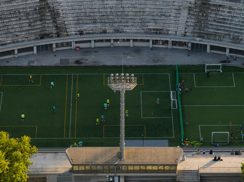 Aerial view of Tasmajdan Stadium with people playing soccer on the green field, stadium seating, and a tall floodlight tower, Beograd, Grad Beograd, Serbia.