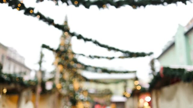 Daytime view of traditional holiday pine garlands decorated with lights stretched across a historic European city square during winter season.