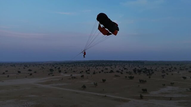 Aerial drone orbit around paraglider flying over the Thar Desert near Khuri, Jaisalmer, Rajasthan, India