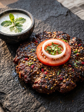 Pakistani Grilled Chapli Kebab with Tomato and Onion on Stone Plate