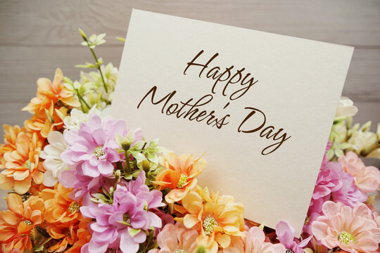 Happy Mother's Day text written on paper card with flowers decorations