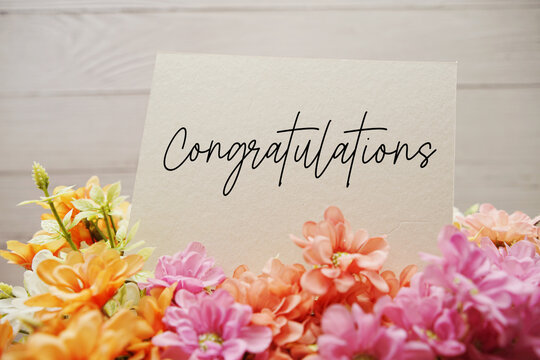 Congratulations text written on paper card with flowers decorations