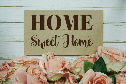 Home Sweet Home text on paper card with rose flowers bouquet on wooden background