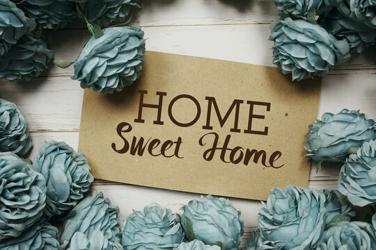 Home Sweet Home text on paper card with rose flowers bouquet on wooden background