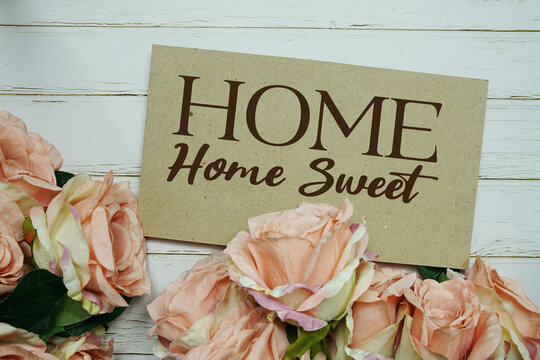 Home Sweet Home text on paper card with rose flowers bouquet on wooden background