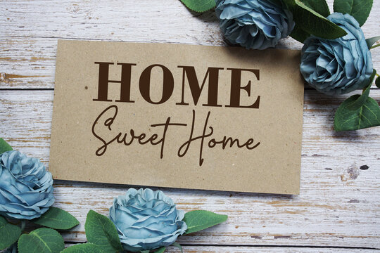 Home Sweet Home text on paper card with rose flowers bouquet on wooden background