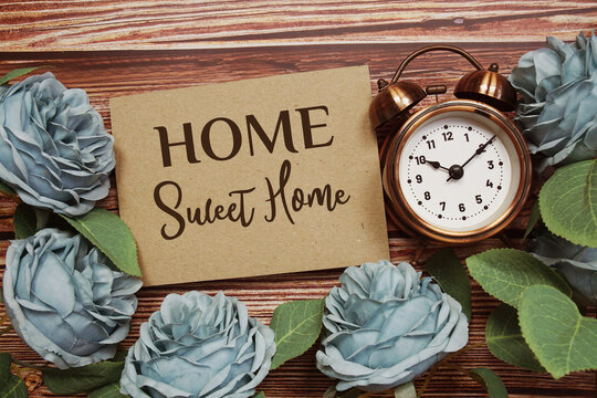 Home Sweet Home text on paper card with rose flowers bouquet on wooden background