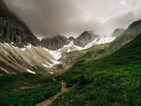 Dramatic alpine panorama from the Mindelheim Via Ferrata in the Allgaeu Alps, Germany, partially snow covered mountain slopes and rugged peaks emerging through clouds, cinematic adventure travel lands