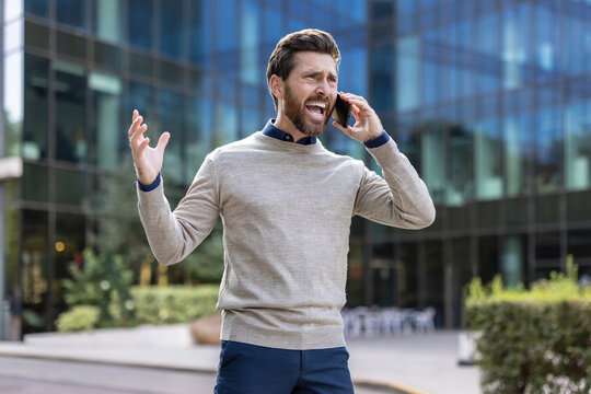 Angry and worried young man talking emotionally on the phone, shouting and waving his arms