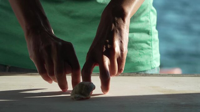Creative finger walking animation around a seashell on wooden table outdoors. Static medium shot.