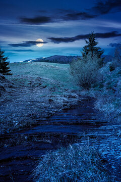 rural scenery in carpathian mountains at night. simple view of a countryside mountain landscape during springtime. full moon over brook near the grassy hills. mysterious fantasy concept