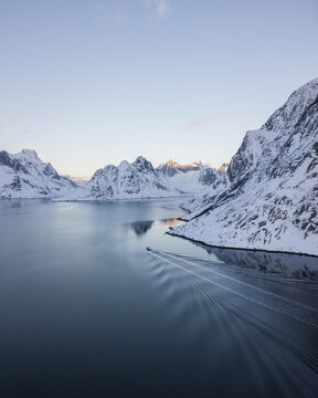 Aerial view, Reinefjord with snowy mountains in winter with a fishing boat, Norway