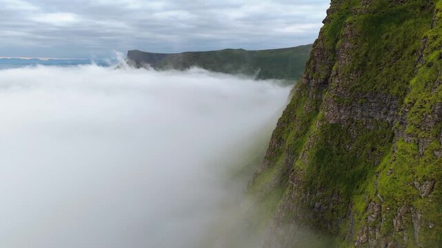 Cinematic aerial view of Benbulben and Benwiskin mountains rising above low clouds in County Sligo Ireland
