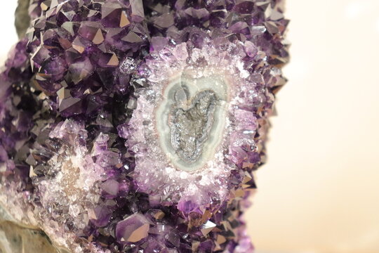 A close-up of a purple geode of amethyst. Mineral, crystal and gemstone and geology. Amethyst druse and raw stone. Purple and violet background with minerals and crystal points. Geogical formation.