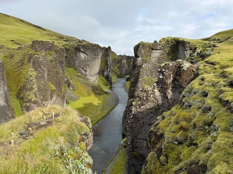 High Angle view of Fjadrargljufur canyon with moss covered rock walls and a winding river in Iceland