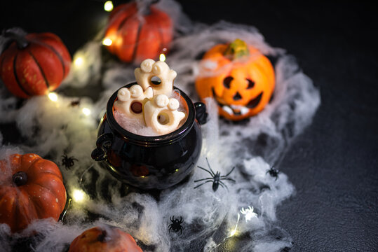 Halloween themed still life with candy cauldron and glowing lights and pumpkins