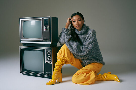 Fashionable Asian Woman Posing Next to Retro Televisions in Studio