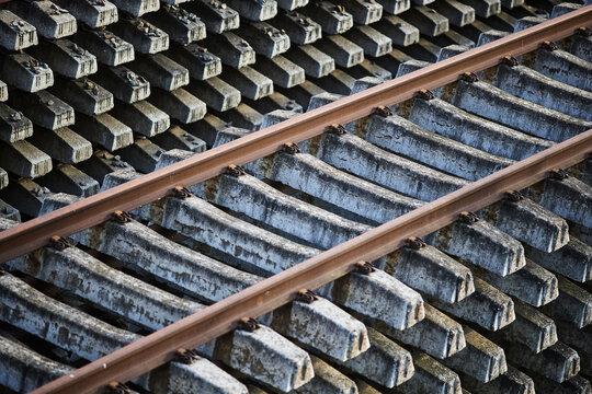 Railway track with concrete sleepers industrial infrastructure transportation materials. Steel rails attached to reinforced concrete ties stacked at construction site, heavy railway maintenance
