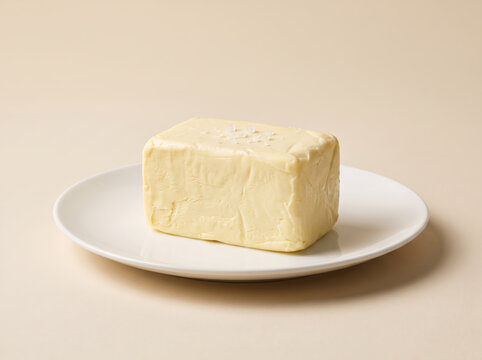 Block of fresh butter sprinkled with sea salt on a white plate