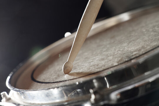 Drumstick hitting drum on dark background, closeup
