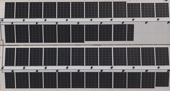 Portugal - 14 August 2026: Aerial view of solar panels installed on factory rooftops, showcasing decentralized renewable energy production.
