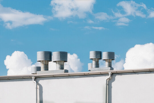 Metal Rooftop Ventilation Vents on White Building Under Blue Sky