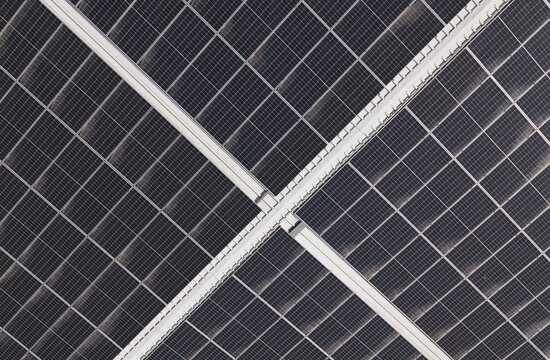 Portugal - 14 August 2026: Aerial view of solar panels installed on a factory rooftop, showing a geometric grid pattern for decentralized energy production.