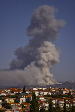 Torre de Moncorvo, Portugal - 20 August 2026: View of a large plume of smoke rising from a wildfire behind a residential area with red-roofed houses.