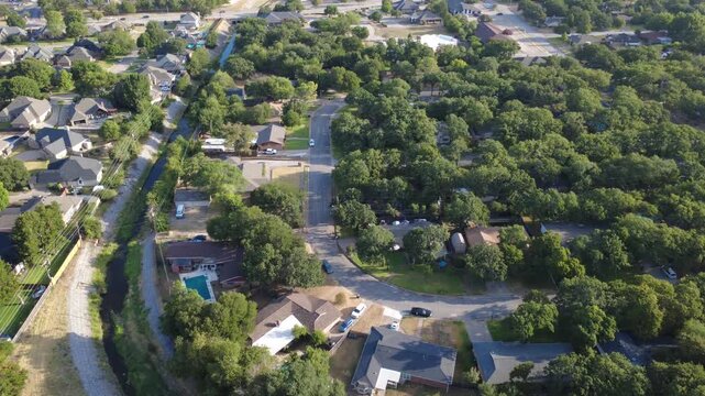 Curved neighborhood lanes follow stone reinforced drainage banks near Little Bear Creek. Distinct brick houses, private swimming pools, wood fencing border suburban waterways, Hurst, Texas