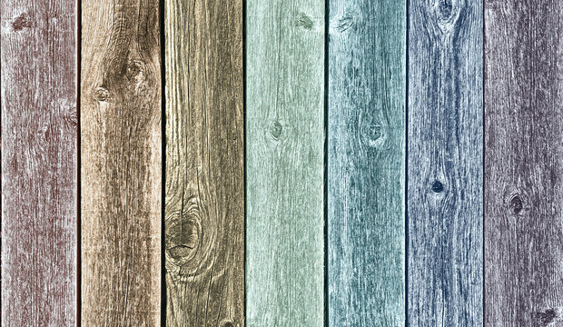 vertical boards of wooden fence section in muted colors of browns, blues, greens