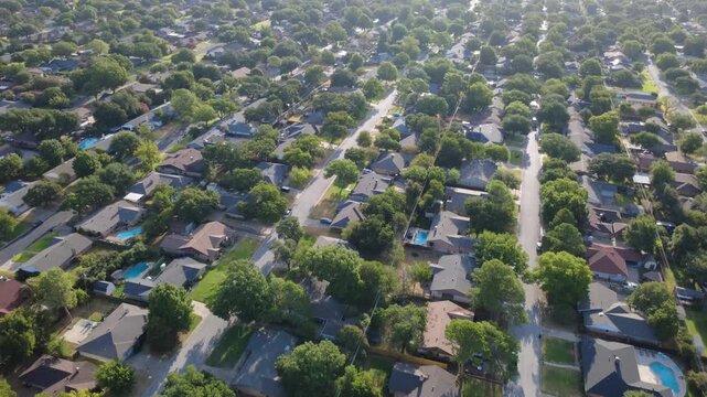 Paved residential corridors cross mature residential enclaves near Little Bear Creek. Shingled rooftops, private backyard swimming pools, dense greenery showcase suburban charm, Hurst, Texas