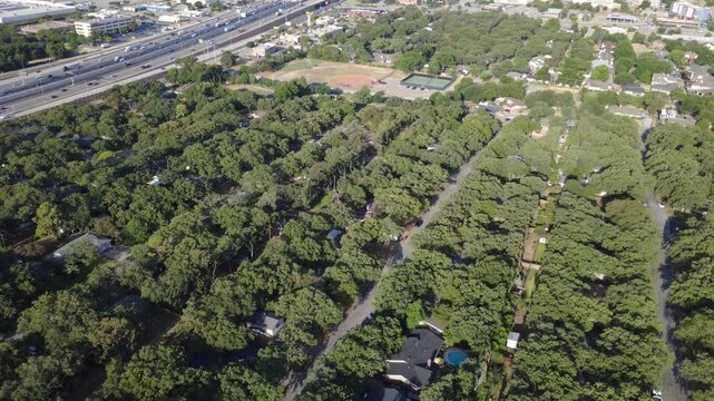 Lush residential greenbelts border multi lane traffic corridors along Airport Freeway. Shaded single family homes, private backyards, sports facilities highlight urban balance, Hurst, Texas