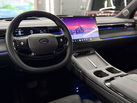 Modern futuristic interior cabin of a Chinese GAC S7 plug-in hybrid SUV. Luxury automobile cockpit with digital dashboard display, large infotainment touchscreen, leather steering wheel, neon light. 